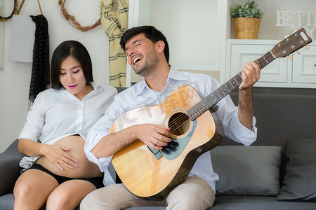 弹吉他的丈夫和生活中美丽的怀孕妈妈