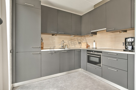 灰色橱柜摄影照片_带灰色橱柜和不锈钢器具的厨房
