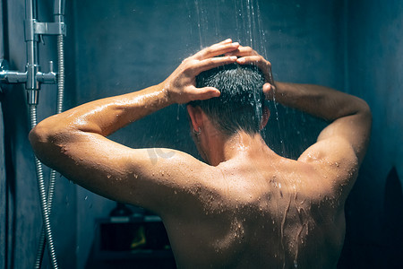 男人在从豪华花洒淋浴喷头落下的水下洗澡用洗发水洗头