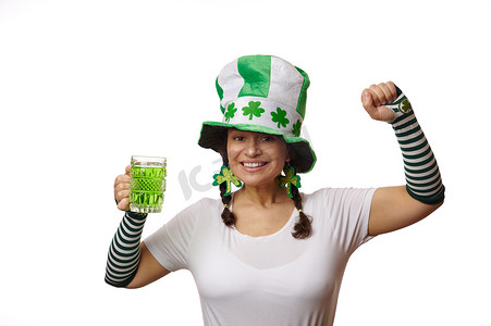 圣帕特里克进步摄影照片_庆祝圣帕特里克酒吧派对的美女，拿着一杯爱尔兰饮料 — 绿啤酒，对着镜头微笑