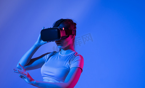 年轻可爱的女人穿着虚拟现实谷歌，和朋友在虚拟世界里玩电子游戏。