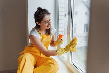 黄色制服清洁窗户的主妇。