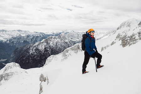 戴着防护头盔和太阳镜的徒步旅行者在雪山徒步旅行时抬头