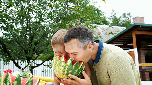 夏天，在花园里，父亲带着四岁的儿子切西瓜吃，玩得很开心，一个男孩非常喜欢西瓜。