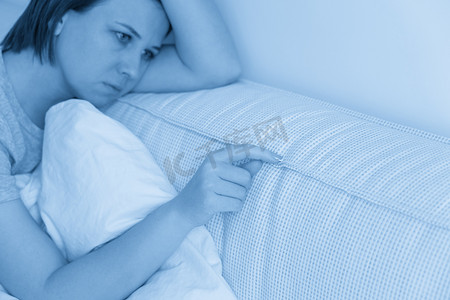 悲伤的女人坐在床上抱着枕头