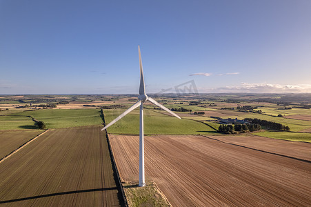 风里发电摄影照片_阳光明媚的日子里，绿色可再生能源农场的孤零零的风力涡轮机