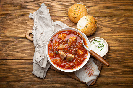 乌克兰罗宋汤，红甜菜根汤配肉，白碗配酸奶油，大蒜面包 Pampushka 和 salo 切片，质朴的石头背景。