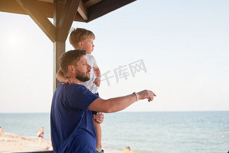 父子一起在外面展示手指海平线背 男人孩子度过假期享受夏天