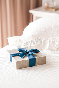 蓝色美容床摄影照片_假日礼物和豪华网上购物送货，卧室床上带蓝丝带的包裹亚麻礼盒，别致的乡村风格