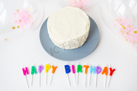 五颜六色的蜡烛与生日快乐刻字隔离在白色背景以及五彩纸屑和便当蛋糕。