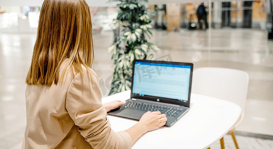 一位女商人坐在咖啡馆里，在电脑前工作。