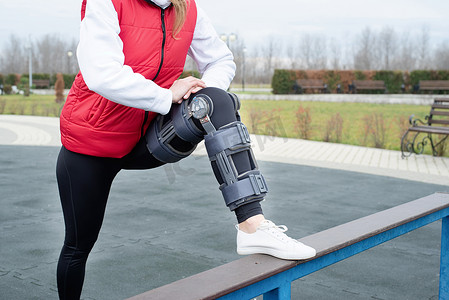 腿部手术后戴护膝或矫形器的妇女在公园散步