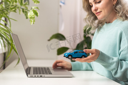 女销售员正在笔记本电脑上记录文档，桌上有汽车模型和笔记本，这是销售合同的概念。
