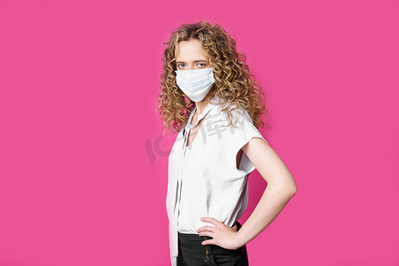 一名脸上戴着医用口罩的年轻女子双手叉腰站立。