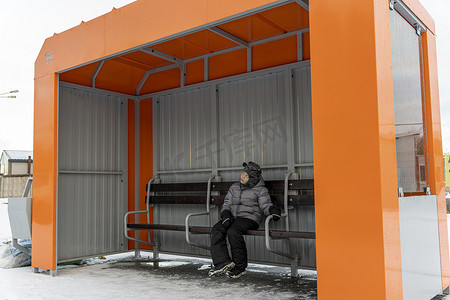 冬天，孤独的孩子在空荡荡的公交车站等车