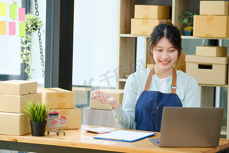 送货清单摄影照片_年轻的亚洲女商人在交付给客户之前检查包裹清单。
