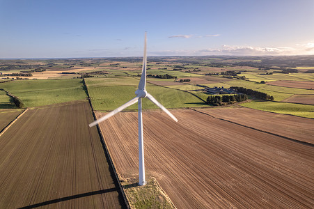 风里发电摄影照片_阳光明媚的日子里，绿色可再生能源农场的孤零零的风力涡轮机