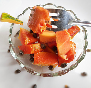 橙色鲜木瓜保存在白色背景中，切块放在带勺子的碗里，富含纤维 维生素 C 和抗氧化剂 增强免疫力 对糖尿病患者和眼睛有益