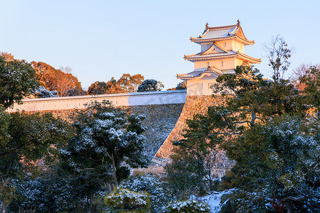 清晨的阳光照在历史悠久的日本城堡上，飘着淡淡的雪