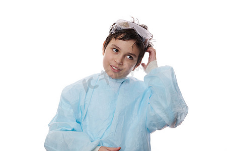 一个英俊的小学生，穿着实验室外套和安全护目镜的可爱少年的白色背景中的孤立肖像