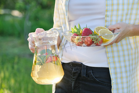 春夏茶点，大自然中的女人拿着一罐草莓薄荷和柠檬