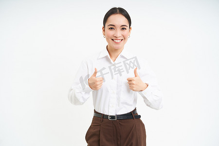 微笑的亚洲女性竖起大拇指，批准促销优惠，推荐产品，站在白色背景中