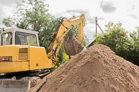 带铲斗的液压活塞系统挖掘机在工业现场卸载一大堆土地。