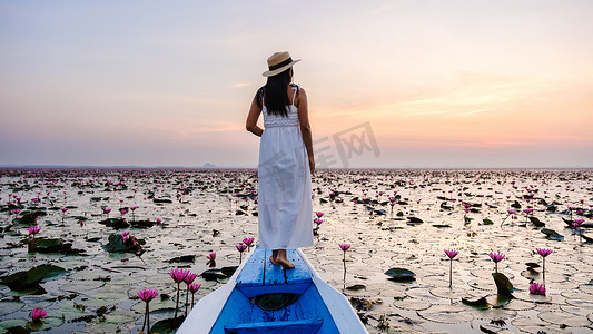 泰国乌隆他尼的红莲海 Kumphawapi 满是粉红色的花朵，亚洲女性在一艘船上。