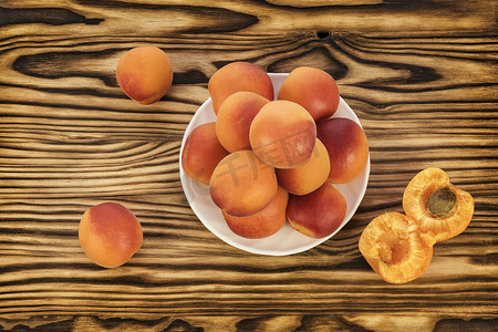 桌子上和白色碟子上放着成熟的杏子