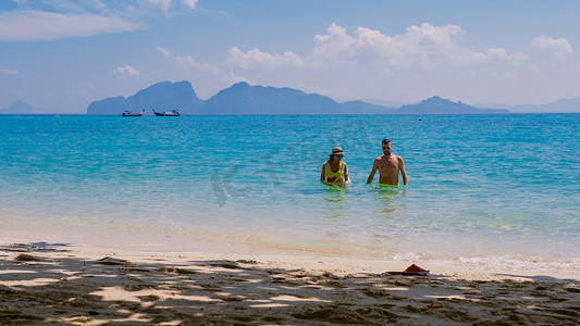 坐在泰国 Koh Kradan 岛海滩上的一对男女的背面
