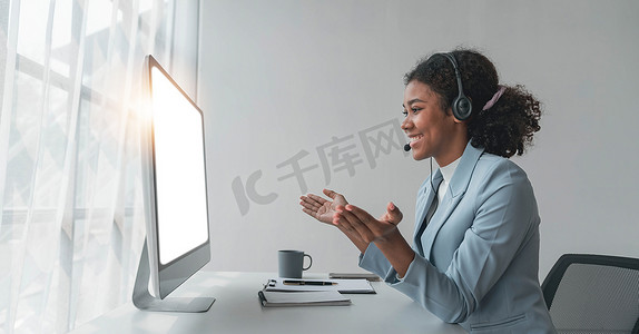 在无线耳机中关闭呼叫中心操作员与客户交谈，在耳机中与麦克风的女性在客户支持服务中通过电话咨询客户，看着电脑屏幕