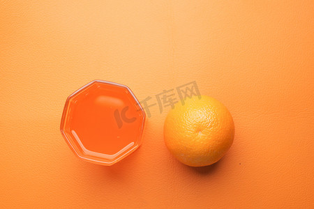 一杯橙汁摄影照片_蓝色背景中带 iece 的一杯橙汁的俯视图