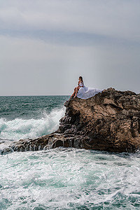 暴风雨中的女人坐在海中的一块石头上。