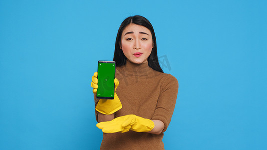 亚洲家庭主妇手持色键模拟手机，带绿屏显示