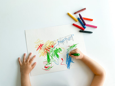 蜡笔标题框摄影照片_小孩在白色桌子上用蜡笔画画。