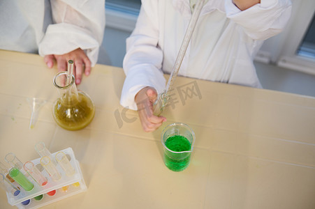 刻度移液管摄影照片_选择性焦点：孩子们在化学课上使用刻度吸管、烧杯、试管进行化学实验