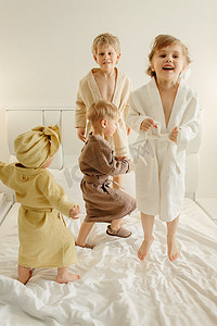 穿着浴袍的快乐孩子在床上玩耍 — 他们跳了起来