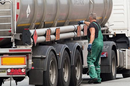 白俄罗斯，戈梅利地区 — 2020 年 8 月 21 日：一名身着工作服的卡车司机抓住接地线或电线将机器接地。