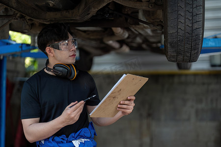 汽车服务维修亚洲人在车库检查汽车状况。