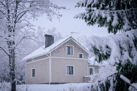 大雪蓝色摄影照片_森林里的房子已经覆盖着大雪和糟糕的天空