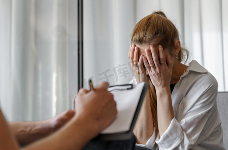 一位男性心理学家咨询一位女性患者，做笔记。