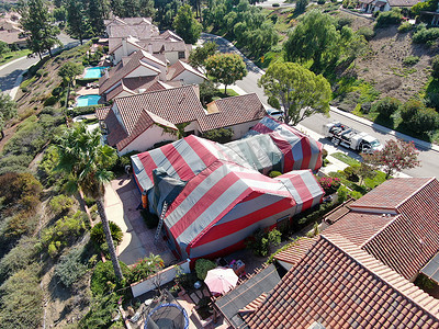 熏蒸摄影照片_在被白蚁熏蒸时覆盖着红色帐篷的住宅别墅的鸟瞰图。