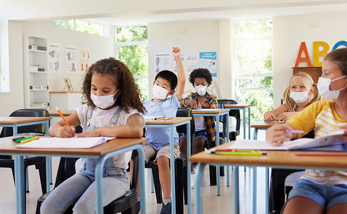 covid 大流行后，年幼的孩子戴着防护面罩在教室里学习。