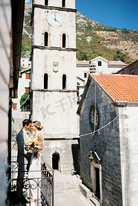 新郎在古钟楼附近的阳台上拥抱微笑的新娘