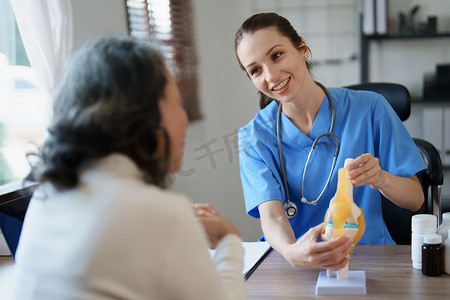 融合与摄影照片_一位女医生与一位老年患者谈论骨关节炎的画像。