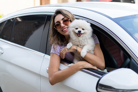 女人和车摄影照片_一个快乐的女人和一条狗在夏天旅行的车里。