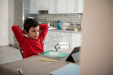 放松的十几岁男孩在家里的数字平板电脑上在线学习、观看网络研讨会、视频课程。
