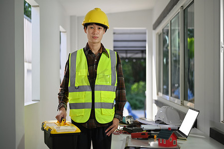 亚洲男工拿着建筑工具箱进行房屋装修的画像。