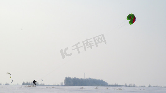 黑衣人在田野里拉着一只绿色的风筝，男人在田野里放风筝。