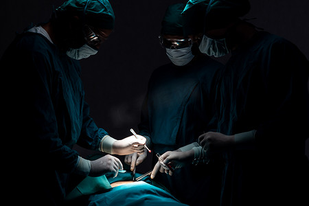 手术室中的病人摄影照片_手术团队在无菌手术室对病人进行手术。